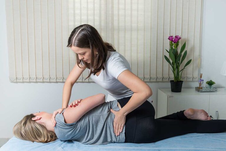 A chiropractor gently adjusting a patient's upper back in a bright, calming clinic room.